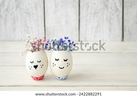 Easter eggs with cute, cheerful faces decorated with delicate flowers on a light background.  Happy Easter holiday concept.  Decoration for the holiday.  Foreground, background image.