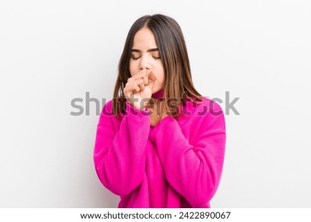 pretty hispanic woman feeling ill with a sore throat and flu symptoms, coughing with mouth covered