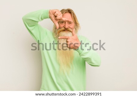 senior cool bearded man feeling happy, friendly and positive, smiling and making a portrait or photo frame with hands