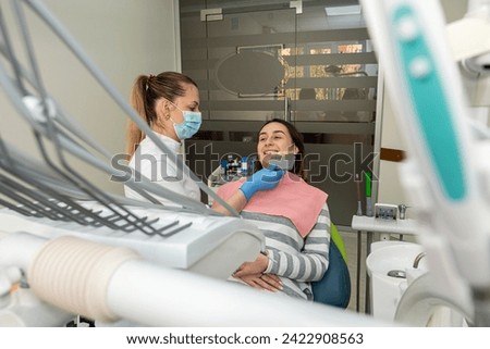 dentist doing correct tooth color with palette with shades of of beauty woman patient. Healthcare bleaching treatment Royalty-Free Stock Photo #2422908563