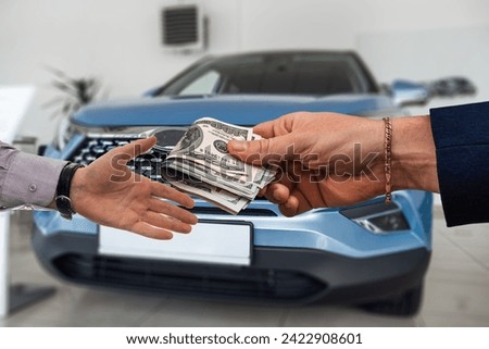 Two businessmen shake hands, buy or rent new auto in modern car showroom. Automobile dealership