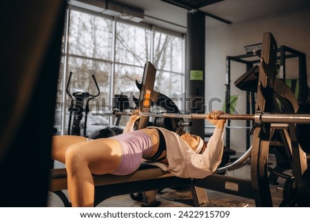 Sports young woman doing exercises with barbell on bench in the gym. Bar Bench Press. High quality photo Royalty-Free Stock Photo #2422915709