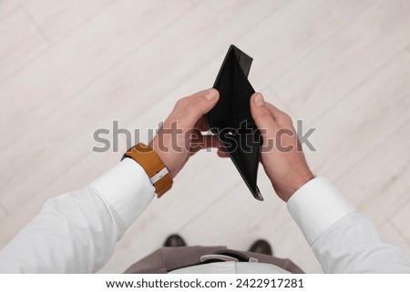 Man with empty wallet indoors, top view