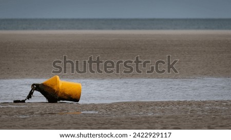 Yellow buoy on the sand beach on the shoreline in low tide