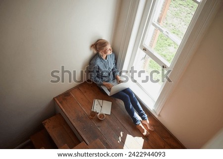 Woman, freelancer and laptop by window, remote work and internet connection on floor for info. Female person, editor and website for research or online news, top view and typing an article on tech