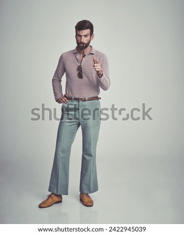 Vintage, fashion and portrait of man with 70s retro aesthetic in gray background of studio. Smoking, pipe and serious person with confidence and pride in funky clothes and unique style from past