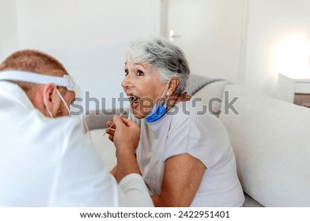 Caucasian female patient visiting her doctor's office and getting tested for COVID-19 by her doctor who's wearing a protective face mask and using a cotton swab. PCR test of COVID-19 for senior people