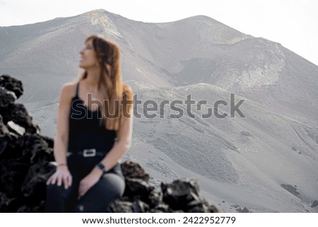 woman looks at the sky smiling in front of a volcano