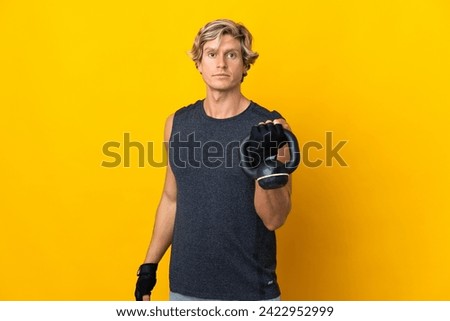 English man over isolated yellow background making weightlifting with kettlebell Royalty-Free Stock Photo #2422952999