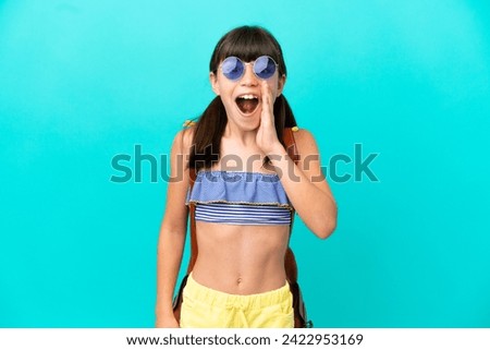Little caucasian kid going to the beach isolated on blue background with surprise and shocked facial expression