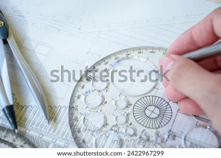 Selective focus of hand drawing line or sketching a house design or construction plan using a pencil and circle ruler on white paper with dividers for design and engineering concepts.