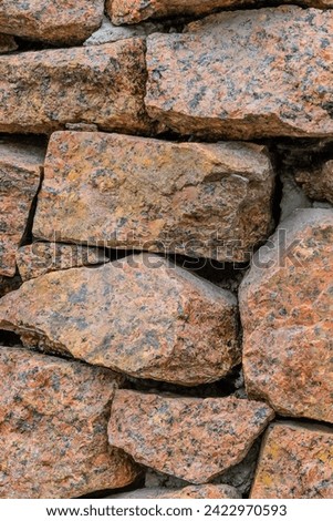 It's photo of a red stone wall of a building. This is close up view of stone background texture.