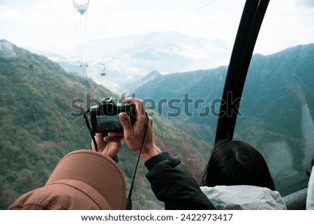 Group of Asian tourists enjoy high angle view of Hoang Lien Son Mountain range, Muong Hoa Valley, Sapa, close-up hand man using compact mirrorless camera take picture, travel destination Vietnam. Park