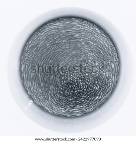 Artistic abstract top to bottom picture of round glass full of sparkling wine with rotating blurred tiny bubbles on its surface 