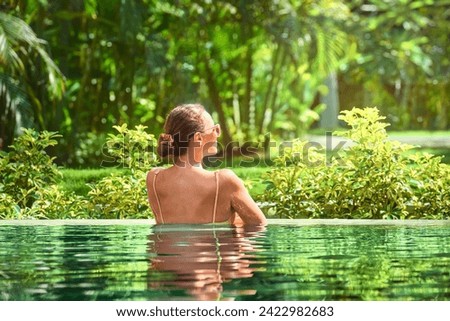 Attractive young woman relaxing on a spa's swimming pool.
Travel, happiness emotion, summer holiday concept.