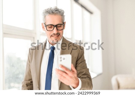 With a focused gaze, this seasoned businessman interacts with a smartphone, demonstrating the integration of cutting-edge technology into his wealth of professional experience. Mature man using phone Royalty-Free Stock Photo #2422999369