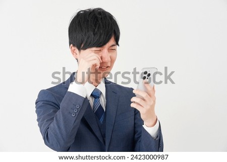 Weeping Asian businessman with the smartphone in white background