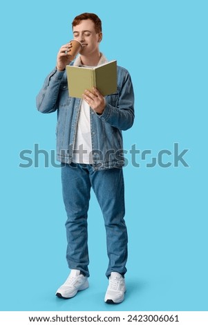 Young man reading book and drinking coffee on color background
