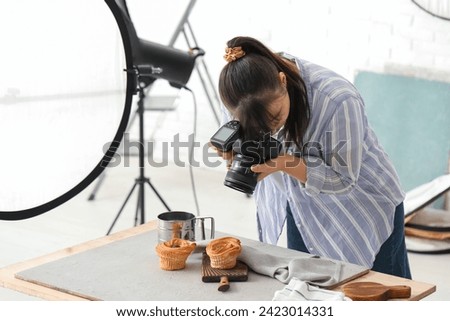 Female food photographer taking picture of tasty cakes in studio