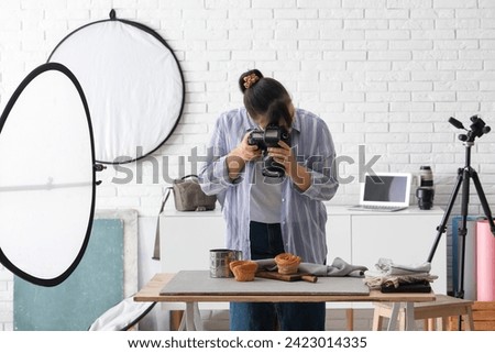 Female food photographer taking picture of sweet cakes in studio