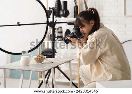 Female food photographer taking picture of cereal rings with milk in studio