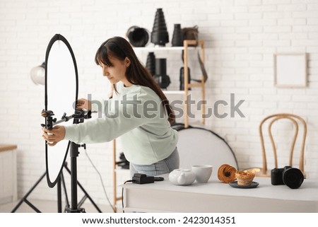 Female food photographer adjusting equipment for shooting in studio