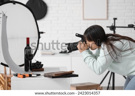 Female food photographer taking picture of wine with grapes in studio