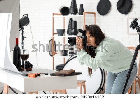 Female food photographer taking picture of wine with grapes in studio