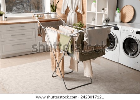 Dryer with clean clothes in laundry room Royalty-Free Stock Photo #2423017121