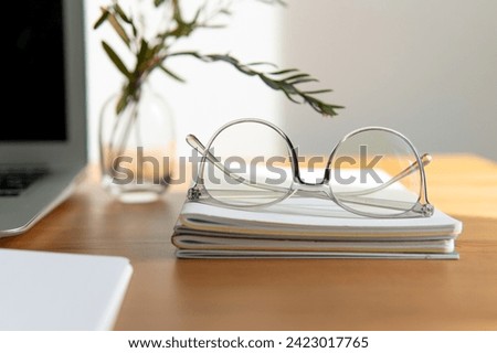 business background. glasses and notebooks are white and grey. notebook in a cage on a beautiful wooden table. Close-up with a blurred background.