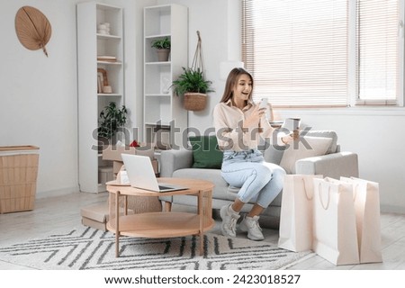 Young woman taking picture of gift card at home