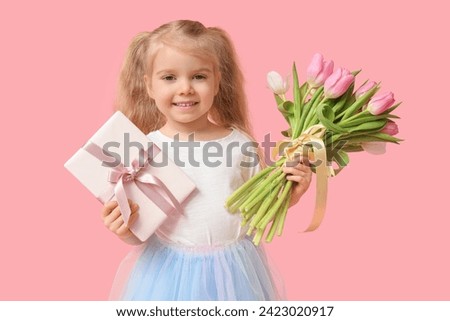 Cute little girl with bouquet of beautiful tulips and gift box on pink background. International Women's Day