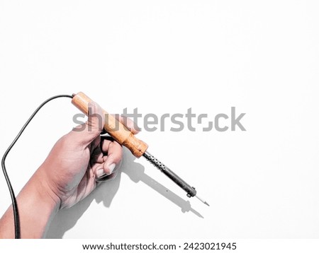 Hand holding a wooden soldering iron with dangling wires, isolated white background Royalty-Free Stock Photo #2423021945