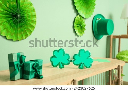 Wooden shelving unit with decorations for St. Patrick's Day celebration near green wall, closeup
