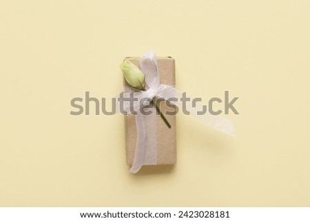 Gift box with beautiful white rose on yellow background. International Women's Day