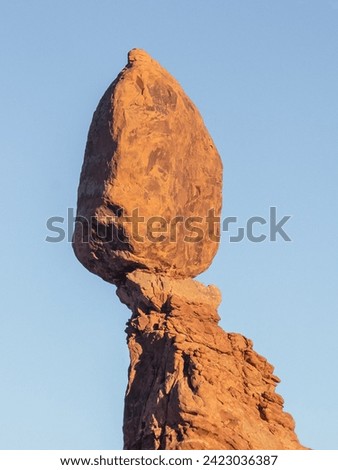 Balanced Rock in Arches National Park defies gravity, a colossal sandstone boulder delicately perched atop a slender pedestal. Nature's whimsical sculpture, shaped by wind and erosion.