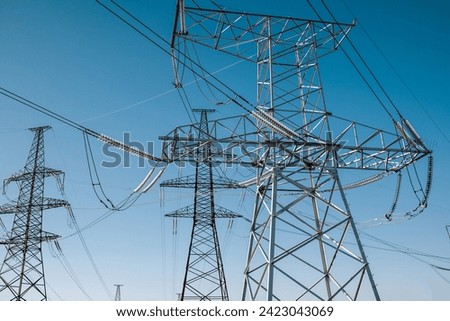 Electric voltage towers, transmission power lines, electricity pylons at sunny sky background. Renewable green energy and clean ecological environment. High quality photo Royalty-Free Stock Photo #2423043069