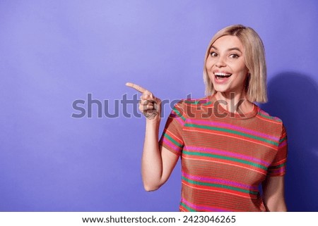 Portrait of surprised attractive young cheerful lady pointing finger banner shows product benefits isolated on violet color background