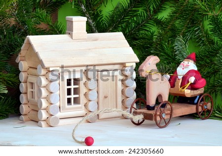 Santa Clause wooden toy nearby wooden cottage