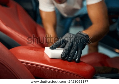 Man cleans a leather armrest with a melamine sponge Royalty-Free Stock Photo #2423061197