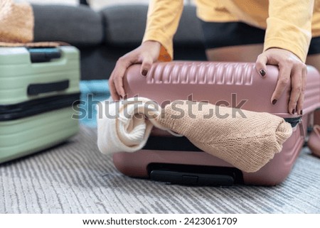 Young Asian Woman packing her suitcase for summer travel.