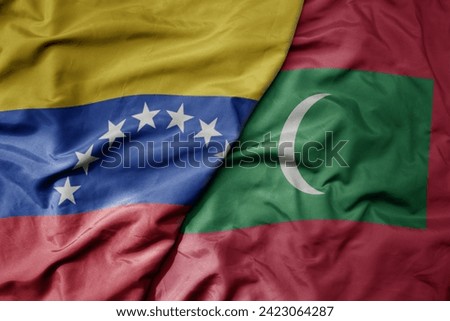 big waving national colorful flag of maldives and national flag of venezuela . macro