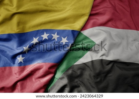 big waving national colorful flag of sudan and national flag of venezuela . macro