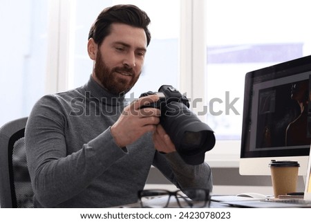 Professional photographer with digital camera at table indoors