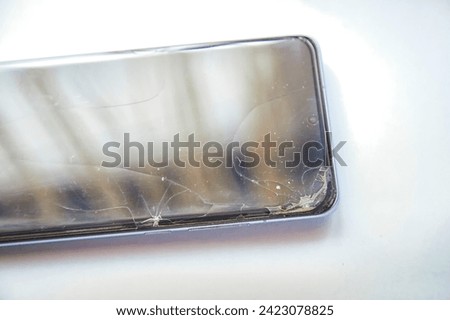Close-Up View of a Cracked Smartphone Screen Against White Background. the detailed texture of a shattered smartphone screen, emphasizing extensive damage to the device