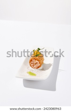 Crunchy crabmeat cannoli on a sleek white dish with a citrus accent, perfect for refined appetizers and modern cuisine. Royalty-Free Stock Photo #2423080963