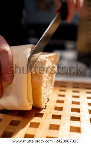 a buffet line in a hotel restaurant a guest cuts bread with knife during continental breakfast