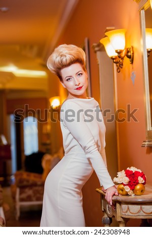 Beautiful young bride in white and red dress with a bouquet in a beautiful room