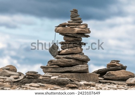 A stack of pebbles on a beach, Cape Enrage Nature Reserve, Bay of Fundy, New Brunswick, Canada. Tourists leave their mark by building these stone cairns. Royalty-Free Stock Photo #2423107649