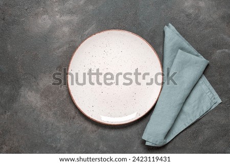 White empty plate with blue linen napkin on a dark background. Top view, flat lay, copy space.